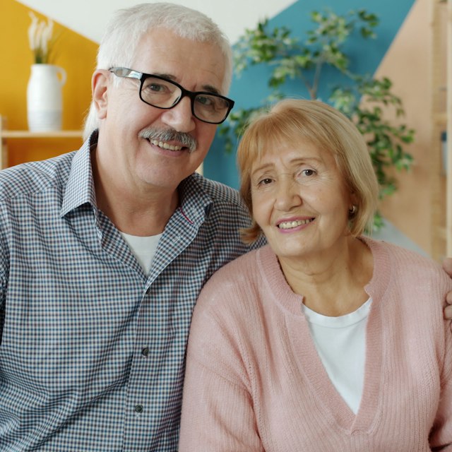 A smiling older couple sitting together at home