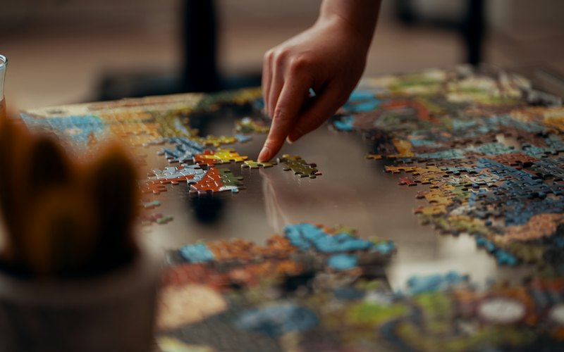 A hand placing a jigsaw puzzle piece