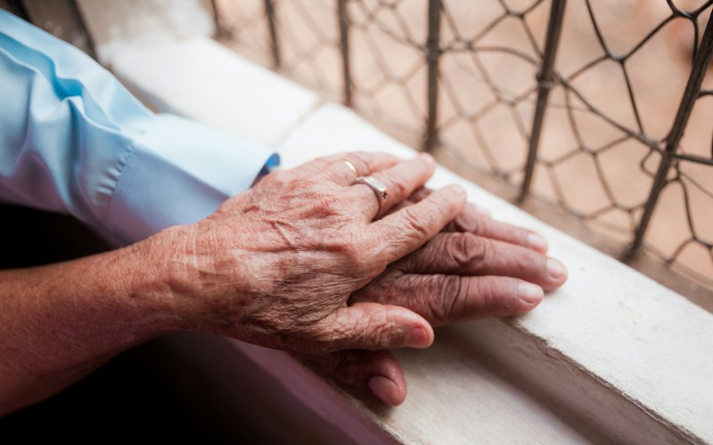 An older person holding the hand of a younger person