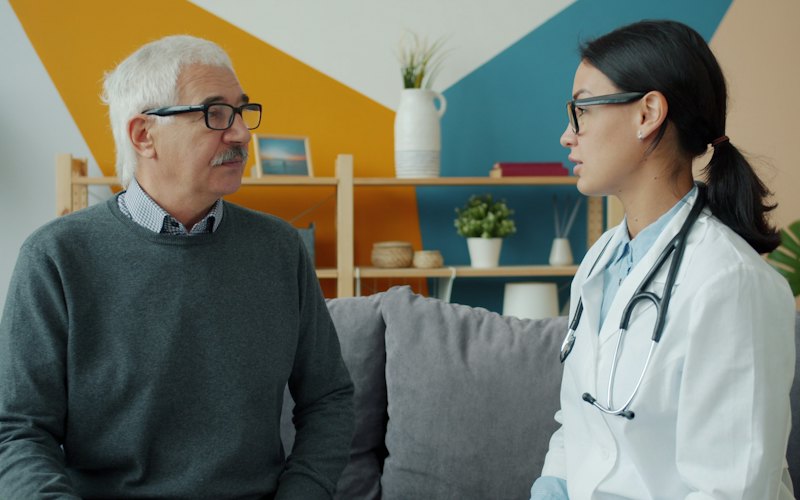A clinician talking with an older man during a consultation