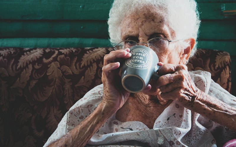 An older woman drinking from a mug