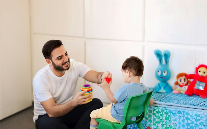 A therapist playing with a young child in a bright therapy room