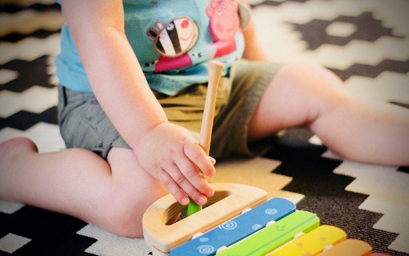 A child's hands working a wooden toy to build fine motor skills