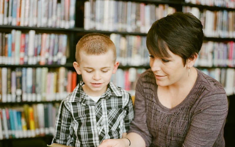 A teacher reading a book with a young boy