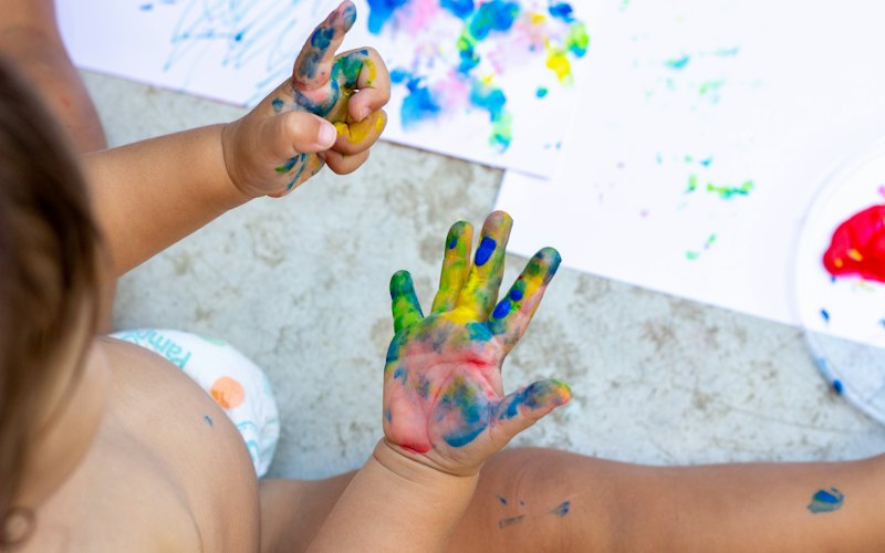 A child's hands covered in colourful finger paint during sensory play